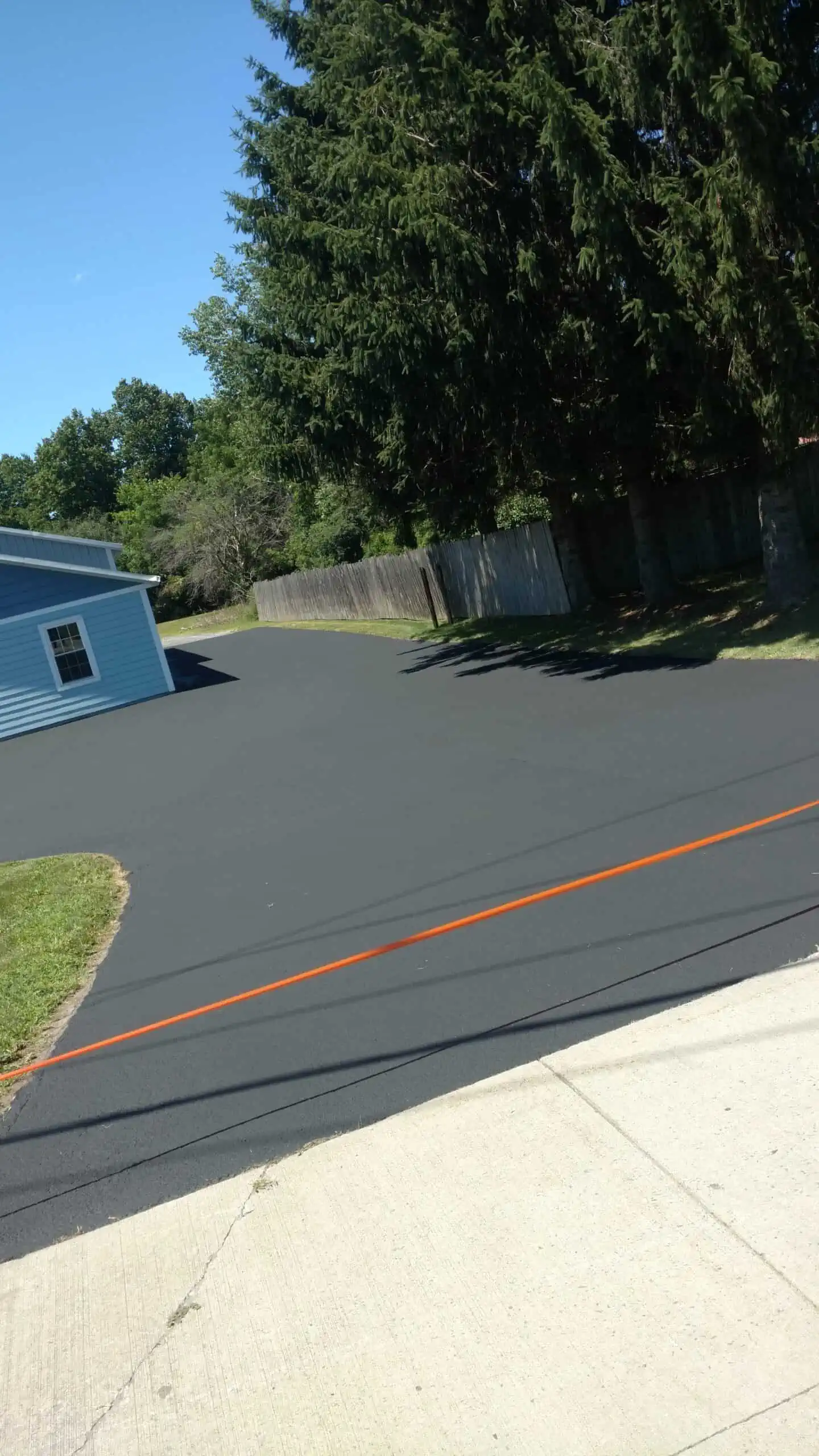 a newly sealed asphalt driveway with parameter tape blocking the entrance while sealcoating cures